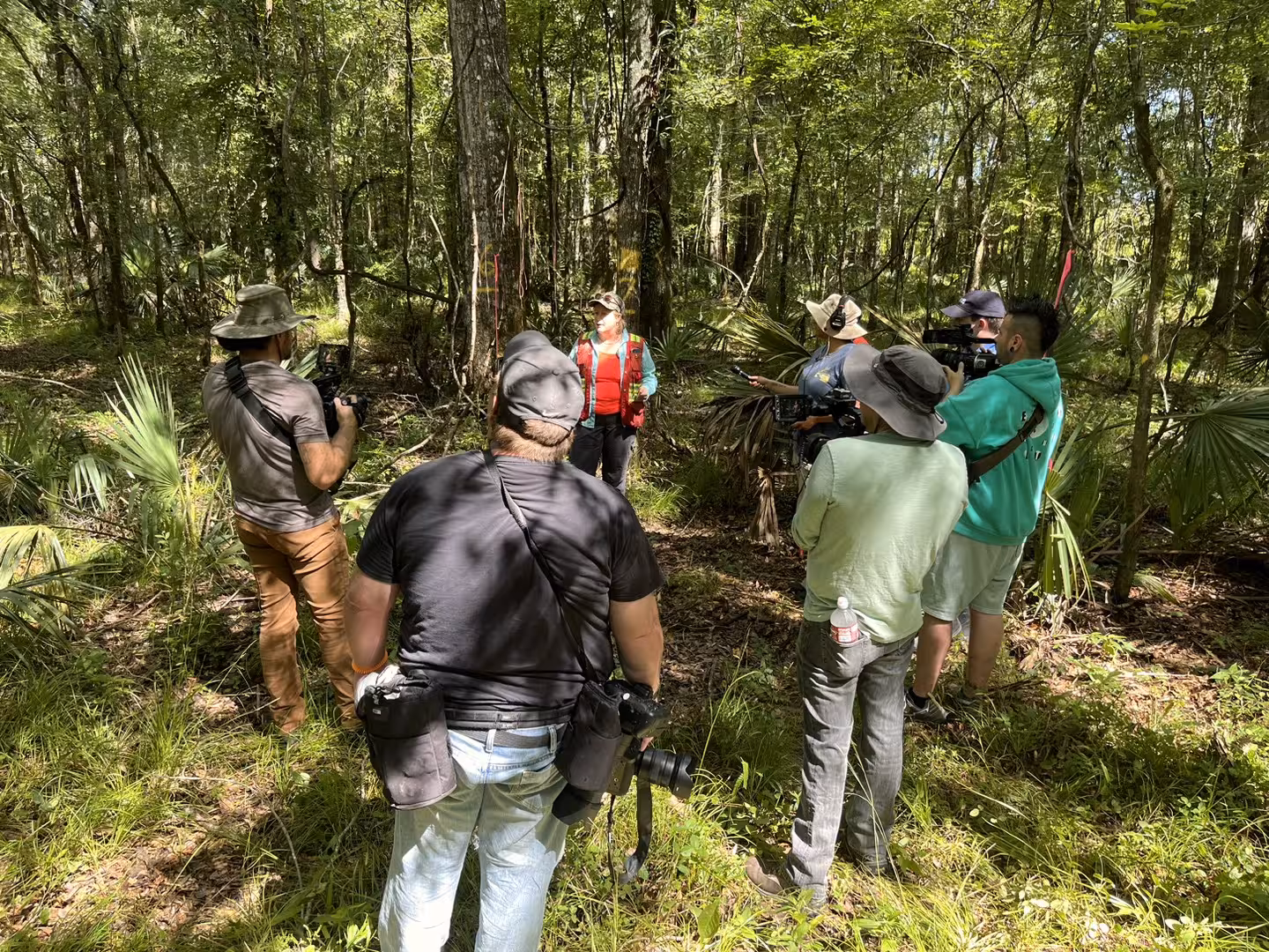 Film crew recording in a wooded outdoor location